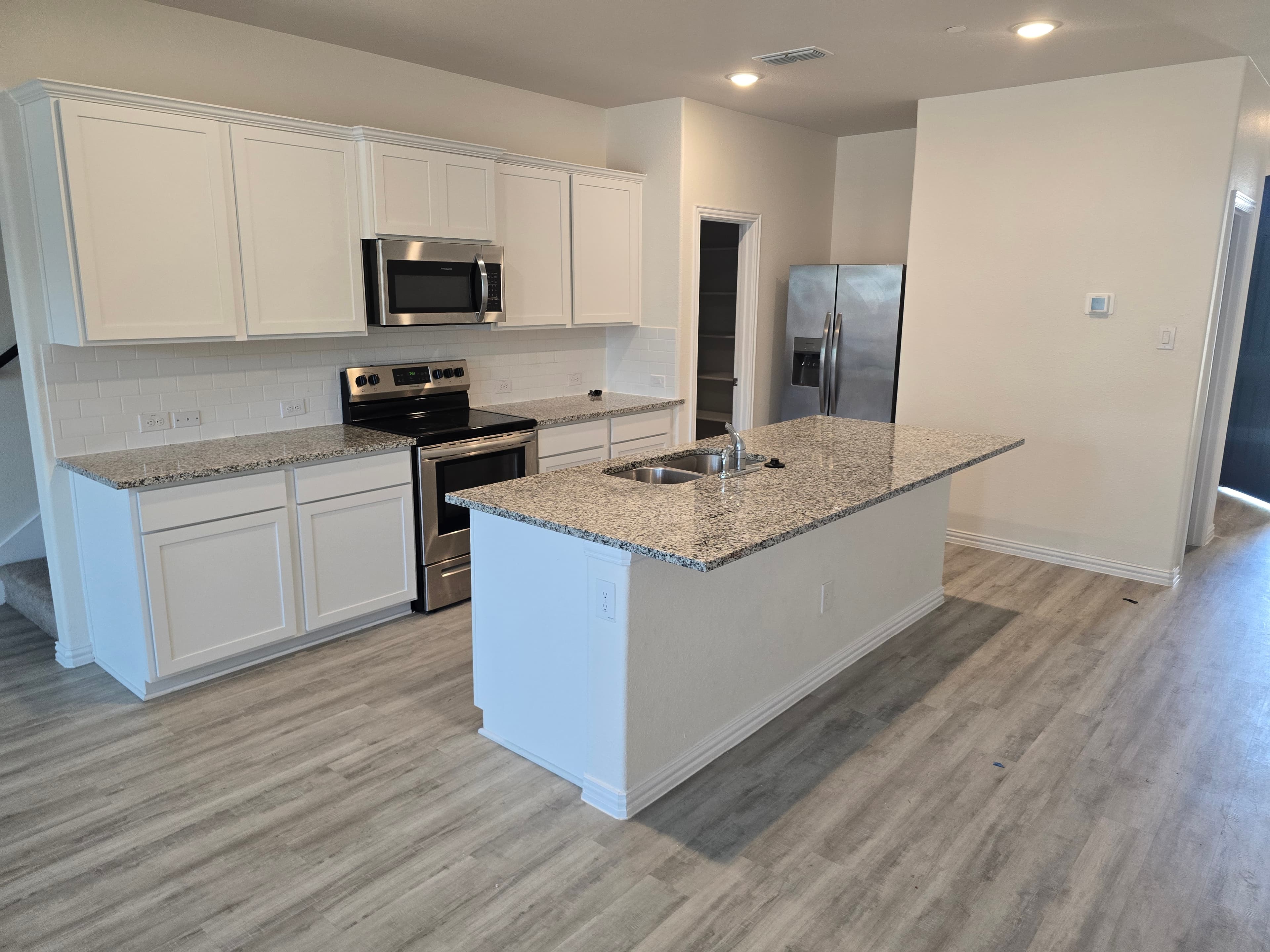 Modern kitchen with white cabinets, granite countertops, stainless steel appliances, and a large kitchen island.