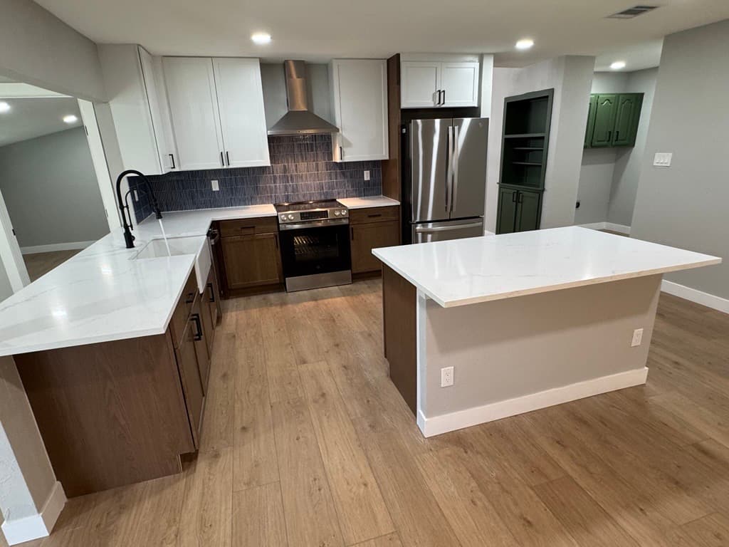 Modern kitchen featuring white and wood cabinets, blue tile backsplash, and white quartz countertops.